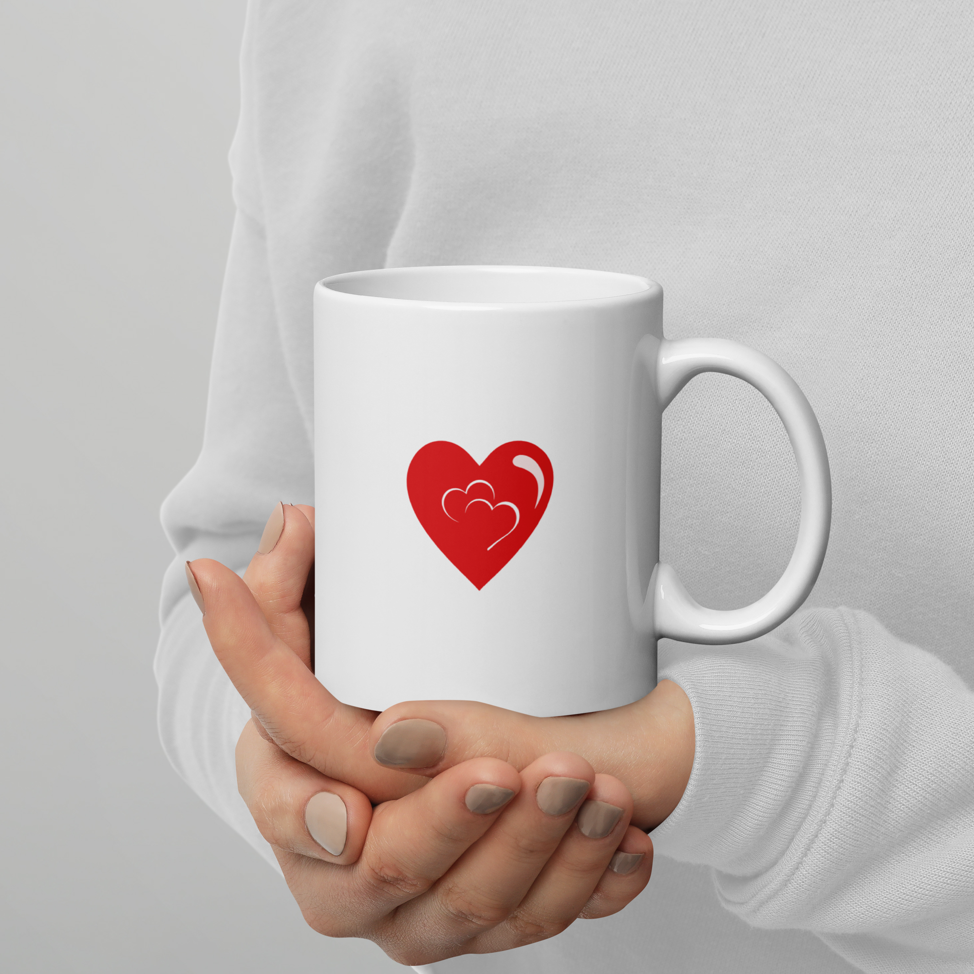 person holding white mug with red heart symbol